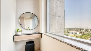 A modern bathroom with a large mirror, a vanity with a countertop, and a view of a cityscape through a large window.