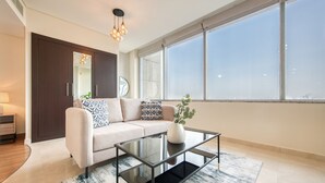 A modern living room with a sofa, a glass coffee table, and a large window.