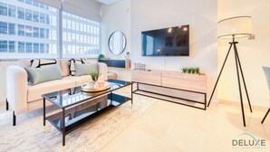 A modern living room with a sofa, coffee table, TV, and floor lamp.