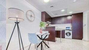 A modern kitchen with dark wooden cabinets, a built-in washing machine, and a dining area with a table and chairs.