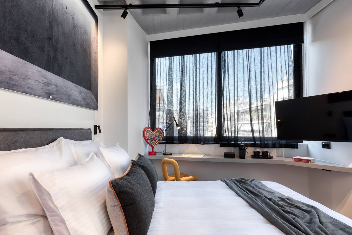 A modern hotel room with a large bed, a desk, and a TV.
