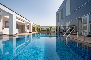 A swimming pool with clear blue water, surrounded by modern buildings with large windows. - Fresh Studio at Sky Gardens DIFC by Deluxe Holiday Homes (Dubai)