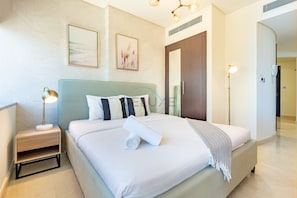 Quarto de hotel com cama, mesa de cabeceira, luminária e obra de arte na parede.