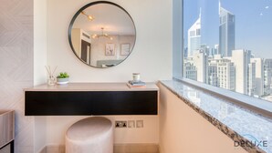 Ein modernes Badezimmer mit einem großen Spiegel, einem Waschtisch mit schwarzer Arbeitsplatte und Blick auf eine Stadtkulisse durch ein großes Fenster.