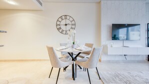 Un comedor moderno con una mesa redonda, cuatro sillas, un reloj de pared y un televisor de pantalla plana montado en la pared.