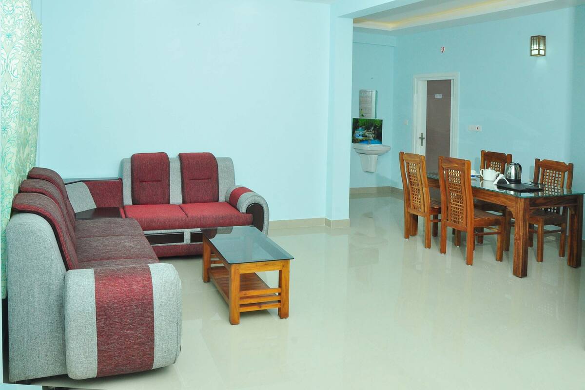 A living room with a sofa, a coffee table, and a dining table with chairs.