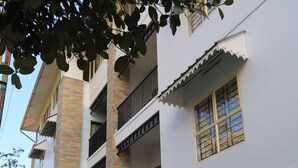 Ein mehrstöckiges Gebäude mit weißer Fassade, Backstein-Akzenten und mehreren Balkonen.
