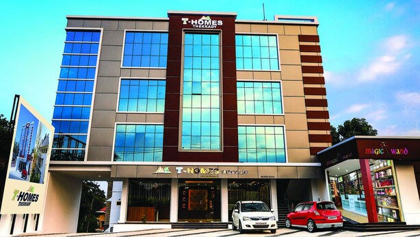 Ein T-Homes Thekkady Hotel mit moderner Fassade, großen Fenstern und gut sichtbarem Eingang.