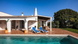 Ein Haus mit Swimmingpool, zwei Liegestühlen und einer Terrassenfläche.