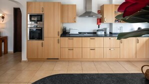 Eine moderne Küche mit Holzausstattung, Edelstahlgeräten und einer schwarzen Arbeitsplatte.