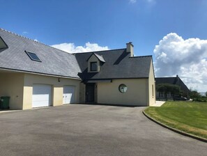 A two-story house with a garage, a small attached structure, and a well-maintained lawn.