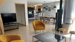 Ett modernt vardagsrum med en soffa, ett soffbord och en tv. Längre in i rummet finns ett kök med en matplats.
