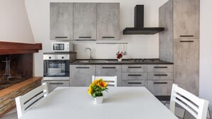 A modern kitchen with grey cabinets, a white dining table, and a vase of sunflowers.