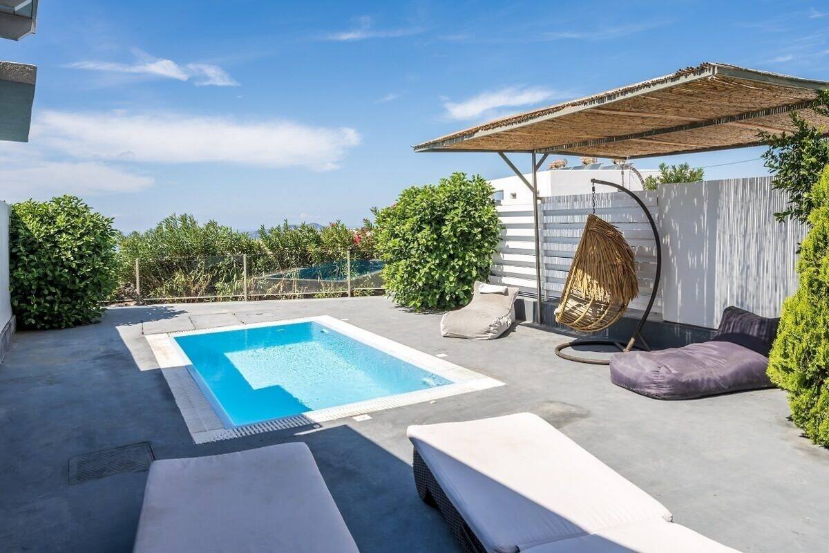 A rooftop pool area with a clear blue pool, lounge chairs, and a hanging chair.
