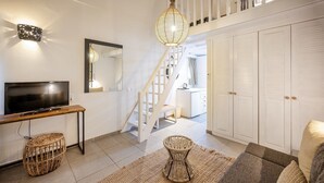 Un salon moderne avec une télévision, des meubles en osier, un escalier et une armoire.