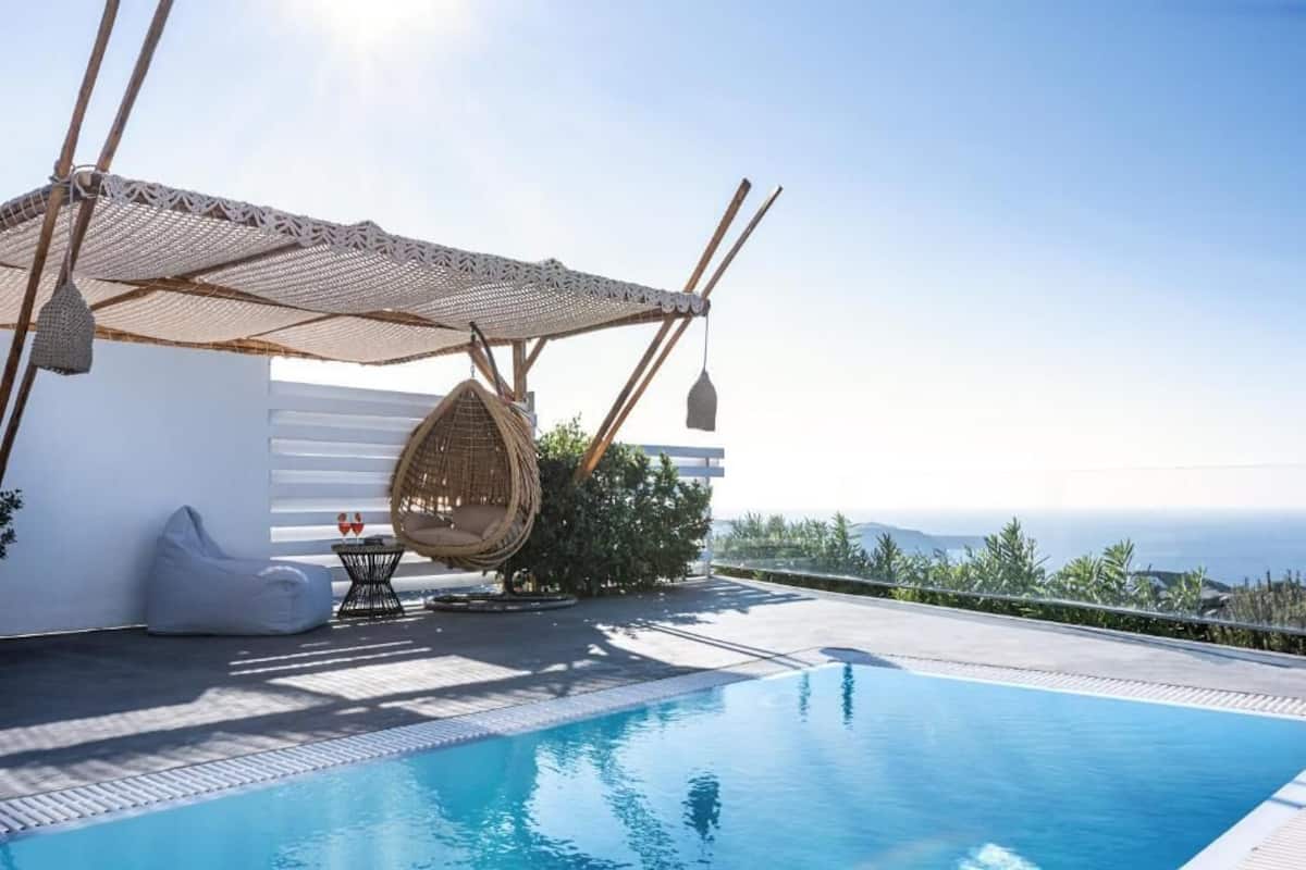 A poolside area with a hanging chair, a small table, and a white wall.