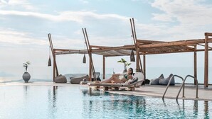 Ein Poolbereich mit einer Holzpergola, Liegestühlen und einer Person, die am Pool entspannt.
