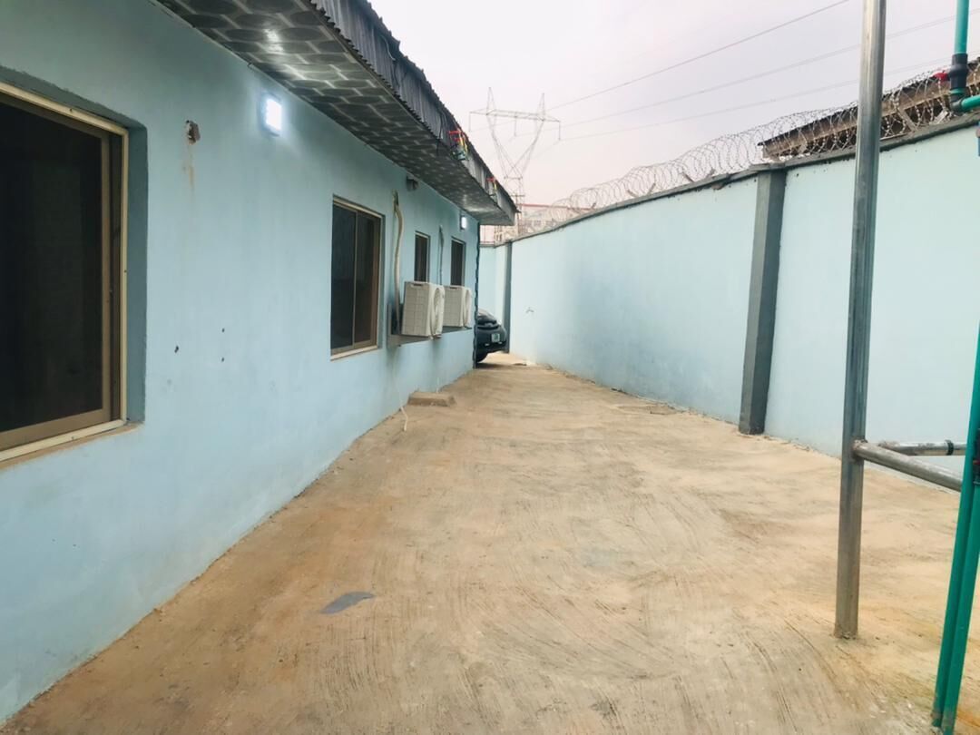 A corridor with light blue walls, air conditioning units, and a concrete floor.