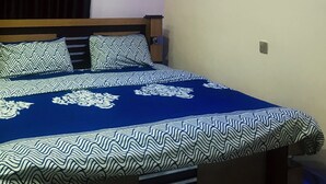 A bedroom with a bed, curtains, a night light, and a framed picture on the wall. - Umbrella Properties Eleyele Ibadan (Ibadan)