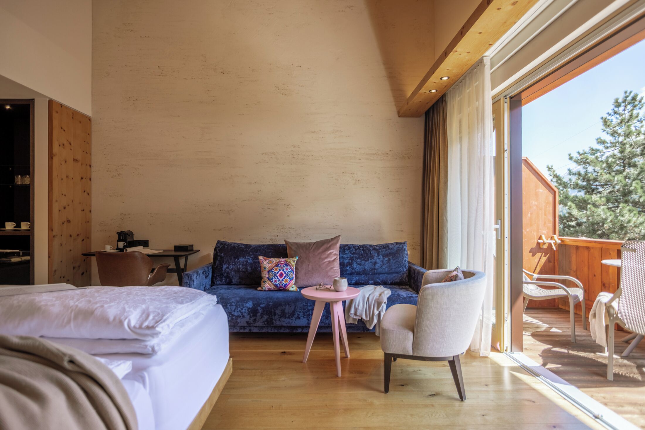 A cozy room with a bed, a blue sofa, a small round table, and a chair.