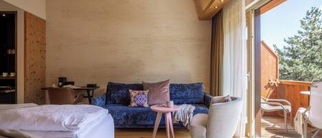 A cozy room with a bed, a blue sofa, a small round table, and a chair.