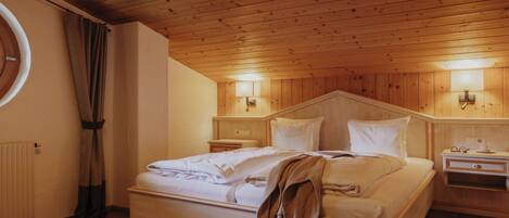 Habitación con paneles de madera, una cama, mesitas de noche y una lámpara de pared.