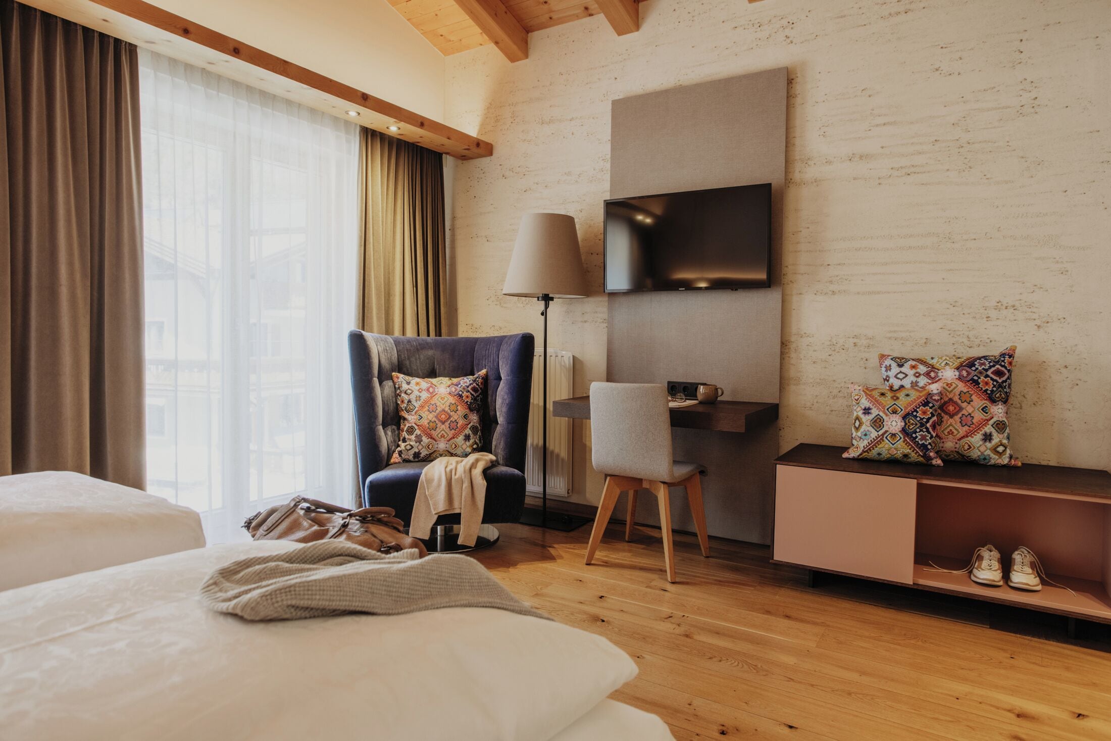 Hotelkamer met een bed, een stoel, een bureau, een televisie en uitzicht op de stad.