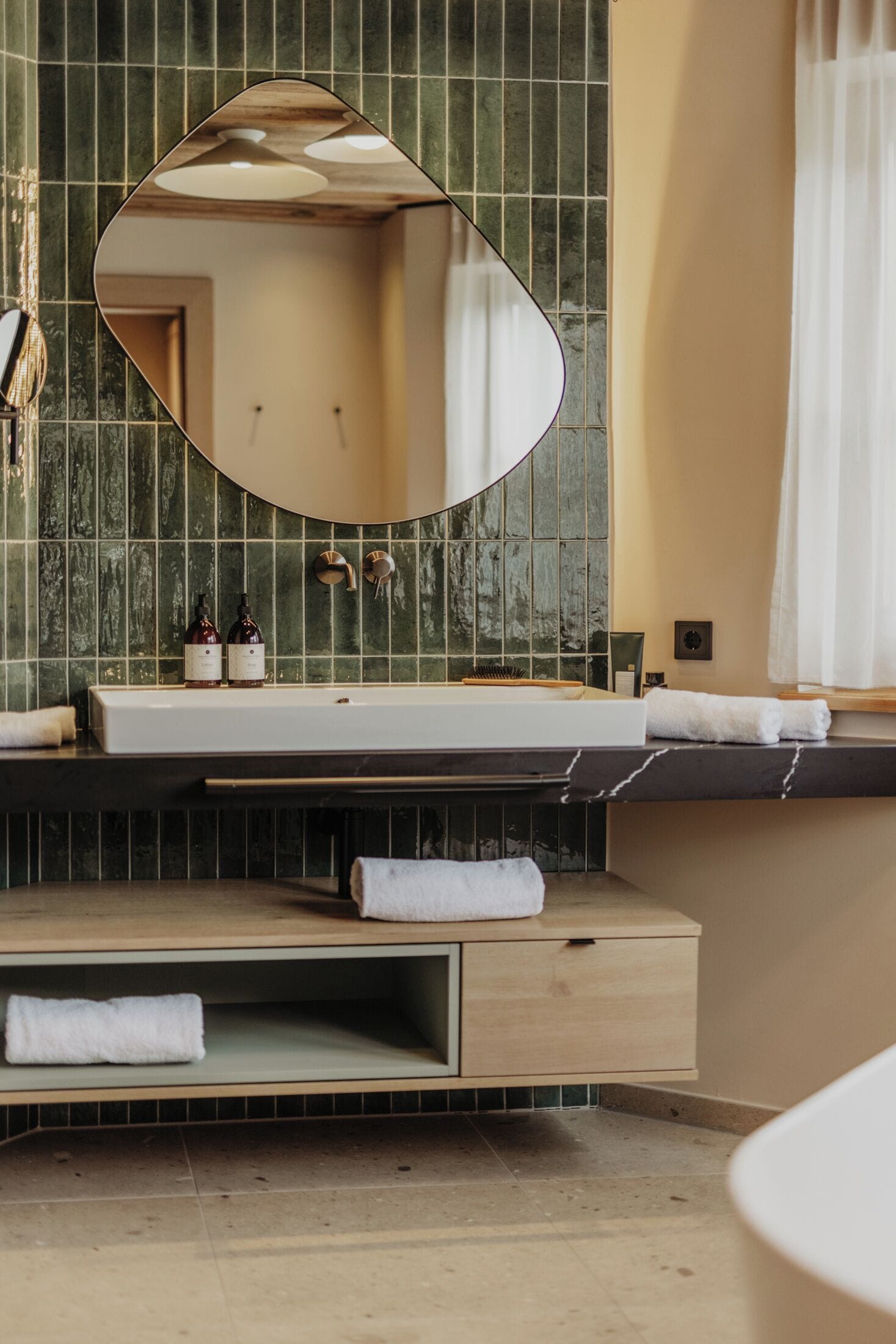 A bathroom with a large mirror, a sink, and a towel rack.