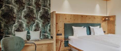 Un dormitorio moderno con cabecera de madera, una butaca tapizada de verde y una mesita de noche.