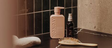 Una encimera de baño con una toalla, una botella de Champú Aveda Moisture y un cepillo de pelo.