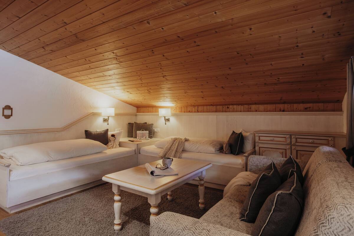 Una habitación acogedora con techo de madera, dos sofás blancos, una mesita y una lámpara.