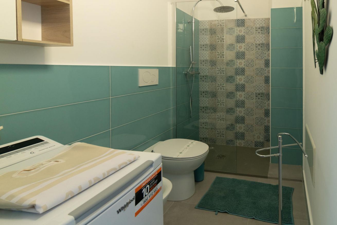 A bathroom with a shower, toilet, and a washing machine.