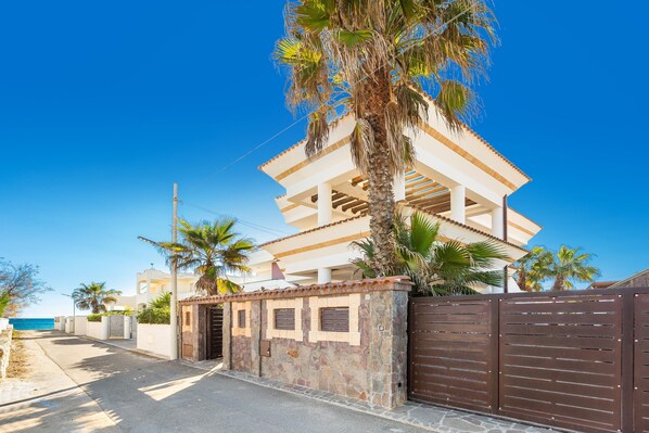 A two-story building with a balcony, surrounded by palm trees and a clear blue sky. - 3218 Villa Eden - Primo Piano By Barbarhouse (Maruggio)