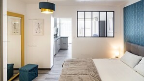 A modern bedroom with a bed, bedside table, and a hanging light fixture. - Apartment "Irrésistible" (LE CAP D'AGDE)