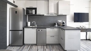 A modern kitchen with a stainless steel refrigerator, microwave, and dishwasher, a sink with a faucet, and a coffee maker on the countertop. - Apartment "Irrésistible" (LE CAP D'AGDE)