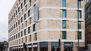 Un hotel moderno con fachada curva, varios pisos y una entrada destacada.
