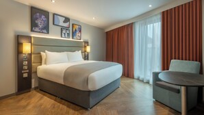 Habitación de hotel con una cama grande, lámparas de noche, un escritorio y una silla.