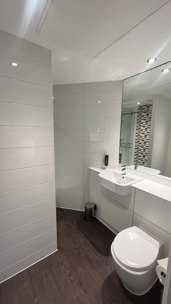 A modern bathroom with a white sink, mirror, and toilet. - Maldron Hotel Finsbury Park, London (London)