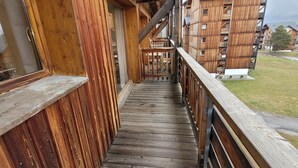 Un balcón de madera con vistas a un edificio con varios balcones.