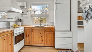 A modern kitchen with wooden cabinets, a built-in oven, a sink, and a white refrigerator. - 3 bedroom amazing home in Glesborg (Glesborg)