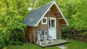 A small wooden cabin with a sloped roof, a door, and two chairs with patterned cushions outside. - 3 bedroom amazing home in Glesborg (Glesborg)