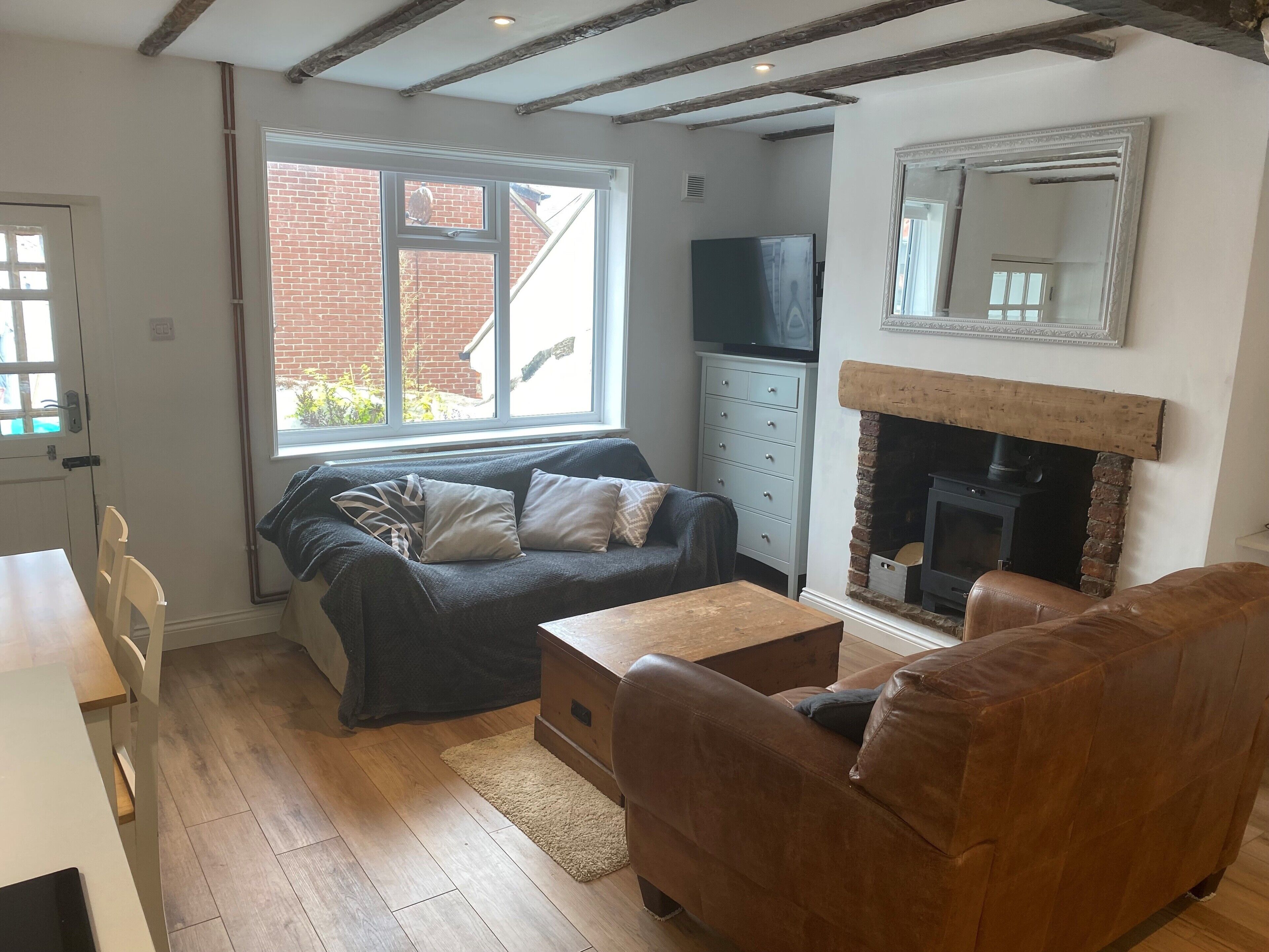 A cozy living room with a sofa, a brown leather chair, a wooden coffee table, and a fireplace.