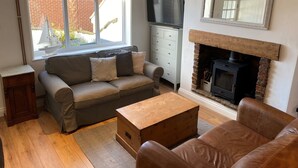 A cozy living room with a sofa, a wooden coffee table, a fireplace, and a TV. - Hideaway (Whitby)