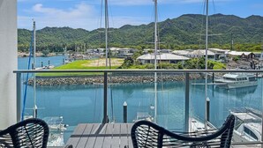 A marina with boats, a clear sky, and a mountainous backdrop.