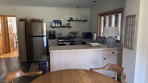 Eine Küche mit Holztisch, Stühlen, einem Kühlschrank, einer Mikrowelle und einem Spülbecken.