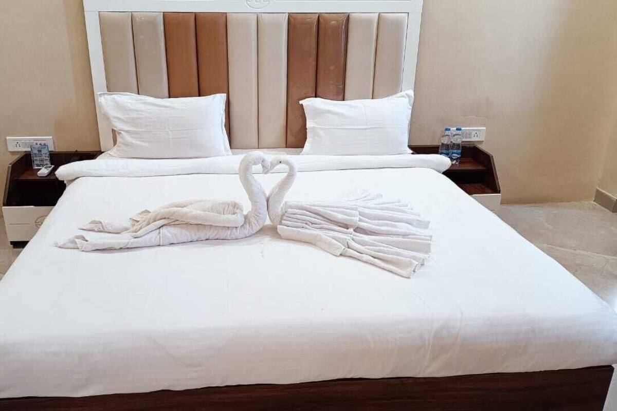 A neatly made bed with a heart-shaped towel arrangement and a wooden headboard.