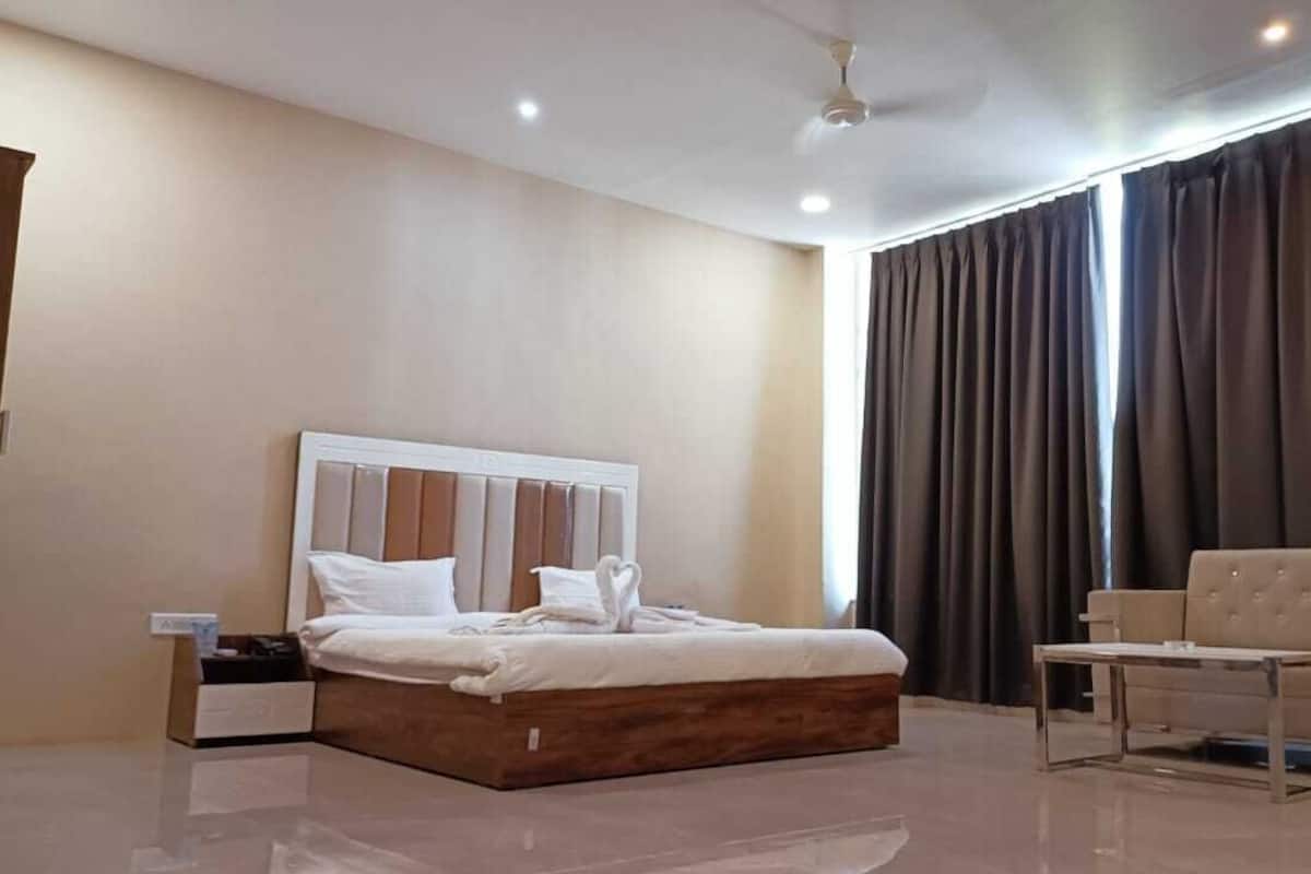 A modern hotel room with a large bed, a bedside table, a sofa, and a ceiling fan.
