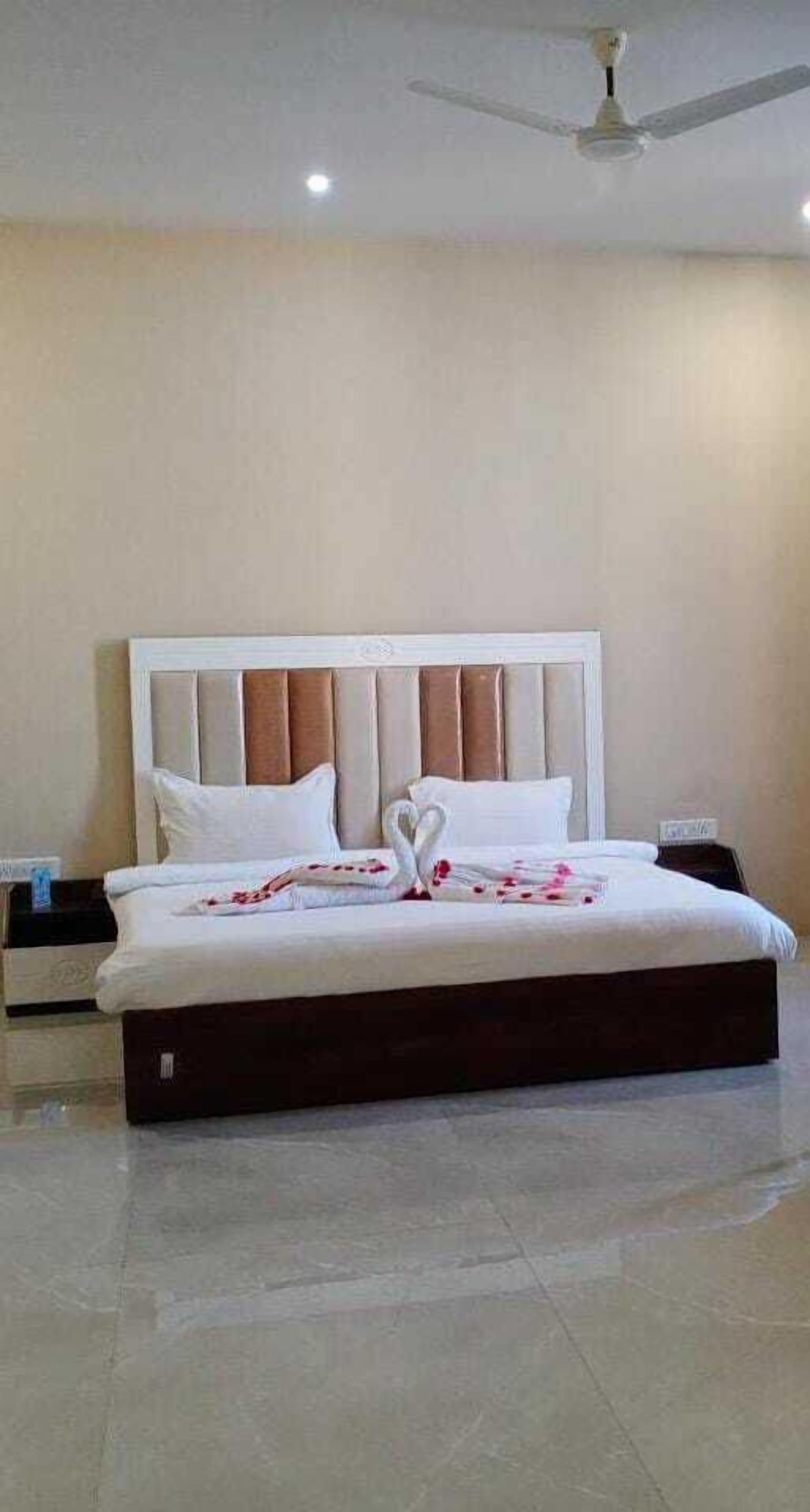 Una cama bien hecha con cabecera, mesita de noche y ventilador de techo.
