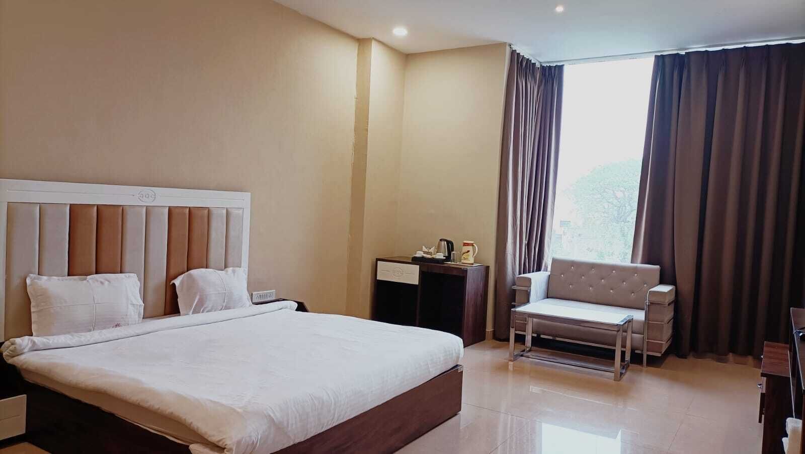 Ein Hotelzimmer mit einem großen Bett, einer Couch, einem Schreibtisch und einem Fenster mit Vorhängen.