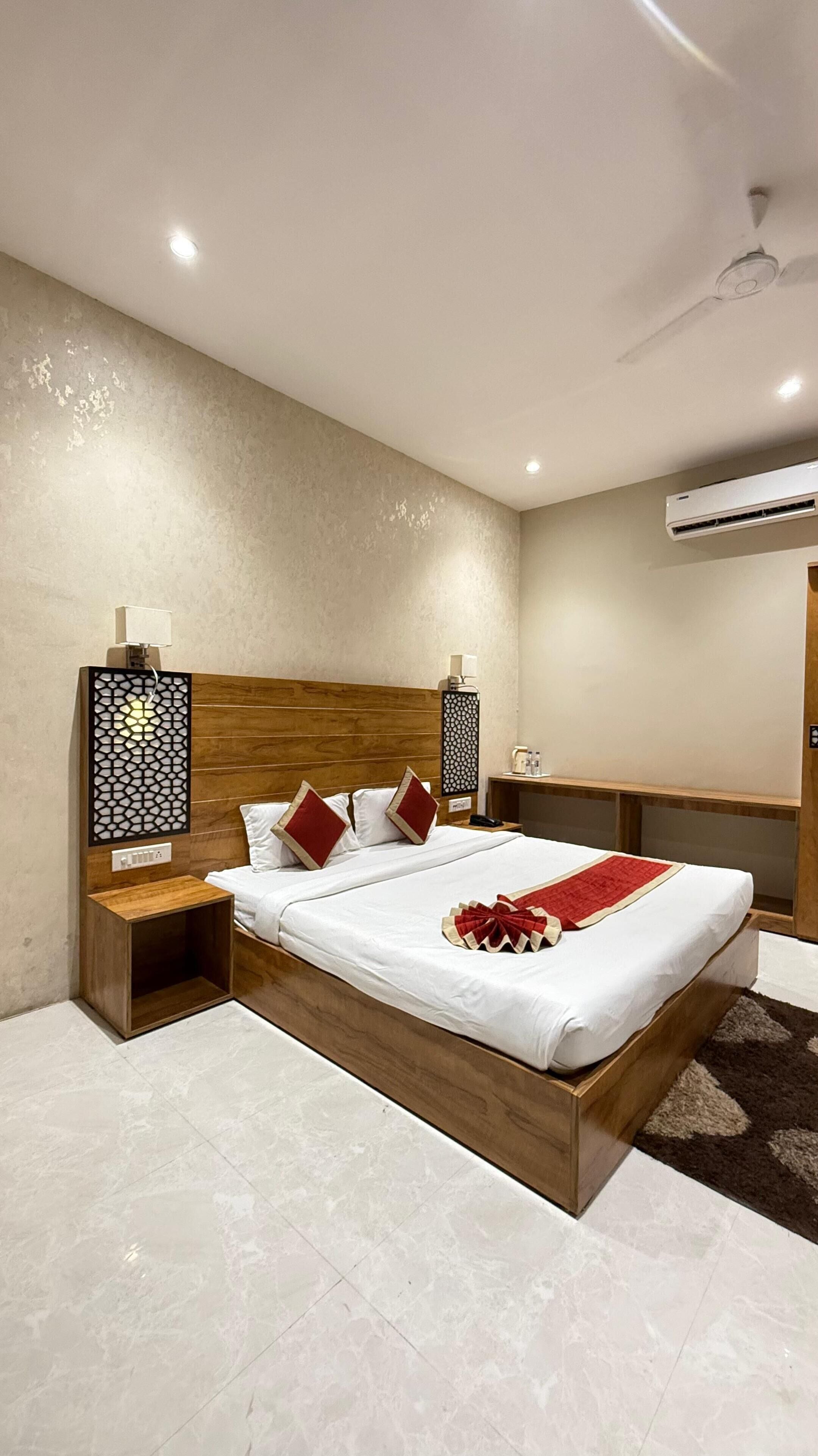 A modern hotel room with a wooden bed, two bedside tables, a decorative wall panel, an air conditioning unit, and a small wooden cabinet.